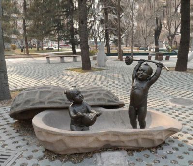 手拿莲蓬和石榴的小孩铜雕在花生壳里的荷花雕塑