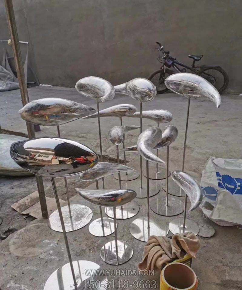园林中站立一群不锈钢镜面鱼雕塑