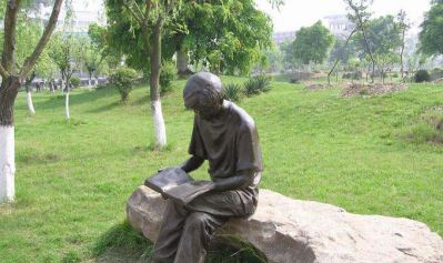 公园草坪玻璃钢仿铜坐着石头上的男孩读书雕塑