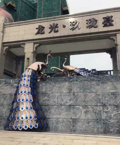 小区墙上两只有限的不锈钢镂空孔雀雕塑