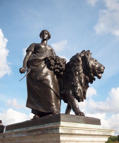 广场拿着镰刀和稻子站着雄狮旁边的铜雕女人雕塑