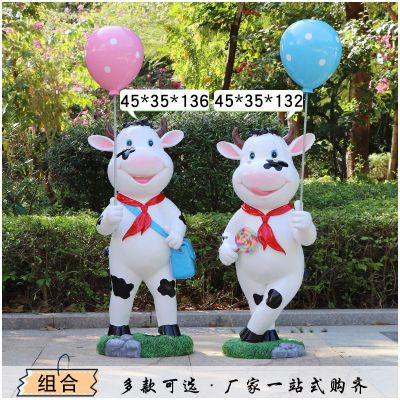 广场站立两个举着气球的玻璃钢牛雕塑