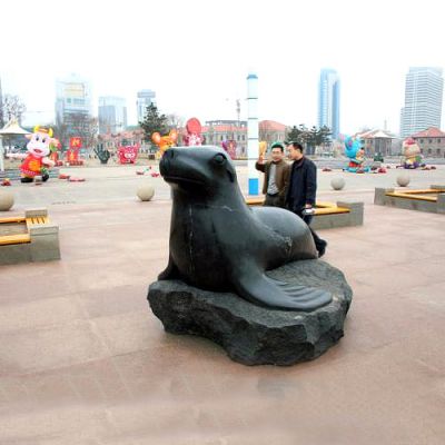 广场上摆放的趴着的青石石雕创意海豹雕塑
