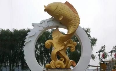 户外景区一只金色不锈钢跃龙门的鲤鱼雕塑