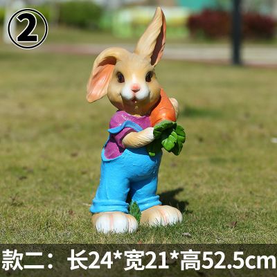 草坪中站立着一只抱胡萝卜的玻璃钢兔子雕塑