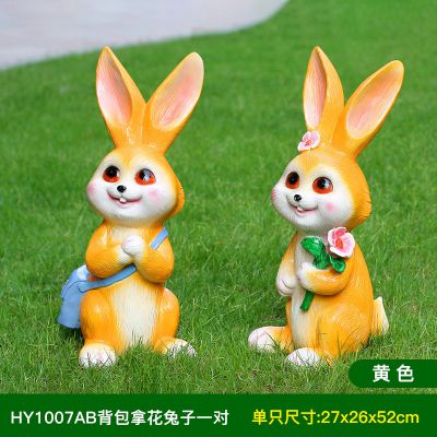 草坪两只黄色背包拿花的玻璃钢兔子雕塑