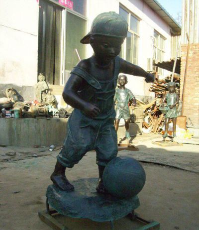 公园青铜踢足球的儿童雕塑