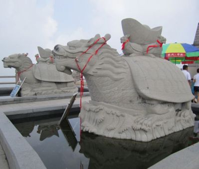 景区摆放的身上背着元宝的砂石石雕创意龙龟雕塑